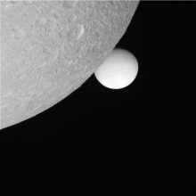 Saturn's icy moon Enceladus (background) slides behind Dione