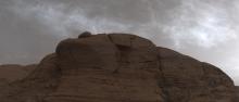 clouds pass above a cliff face on Mars