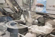 a technician frees bolts on an asteroid sample container