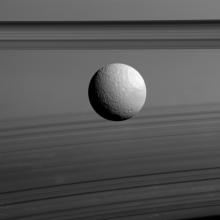 Cassini view of Saturn's moon Tethys against the planet's clouds and rings